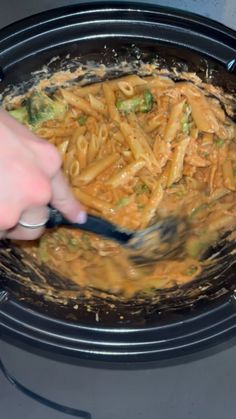 a person is stirring some food into a pot with broccoli and noodles in it