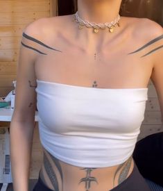 a woman wearing a white top with tattoos on her chest