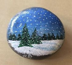 a painted rock with snow and trees on it