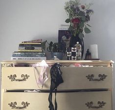 an old dresser with flowers and books on top