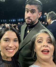 two women and a man posing for a photo in front of an audience at a sporting event