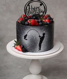 a black and white birthday cake with berries, strawberries, and the silhouette of a man on it