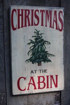 a wooden sign that says christmas at the cabin with a pine tree on it's back