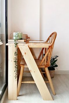 a wooden chair sitting next to a table with a plant on it's side