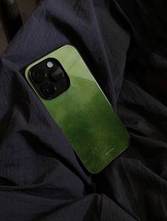 a green iphone case sitting on top of a black cloth covered tablecloth in the dark