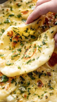 a person is dipping cheese on top of some pizza crusts with parmesan and chives