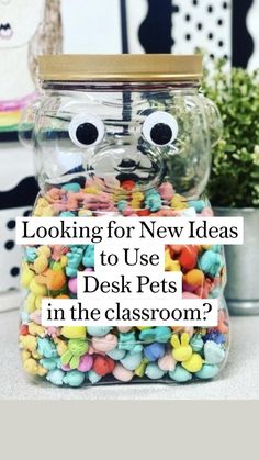 a glass jar filled with lots of candy and eyes on top of a table next to a potted plant