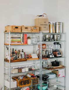 a metal shelving unit filled with lots of kitchen items and storage bins on top of each shelf