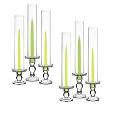 four candles are lined up next to each other in glass vases with green candles