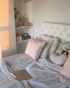 a laptop computer sitting on top of a bed next to two pillows and a teddy bear