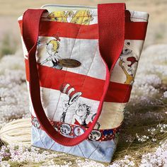 This tote is vibrant and colorful with a fun Seuss character print that comprises the upper portion of bag and medium blue cotton twill fabric make up the bottom and the entire bag is machine quilted with red and yellow thread. The seam where the two halved are joined is covered with a grosgrain ribbon trim that has the Seuss characters Thing One and Thing Two that repeats across the width of the bag. Our wooden Cottage Bags~n~Totes label is featured on the front of the bag. The dimensions of the bag are 10" tall, 10" wide at the top, 6" wide at the base, with a " wide base. Bags handles are made from red cotton webbing and measure 21" in length. The inside lining is made from Seuss print fabric and on one side  a Seuss print side to side pocket with a blue band on the top. The top closes Red Patchwork Shoulder Bag For Daily Use, Red Tote Box Bag With Handles, Red Patchwork Tote Bag, Disney Character Print Multicolor Bags, Multicolor Patchwork Tote Bag, Wooden Cottage, Quilted Tote Bags, Quilted Totes, Dr Seuss