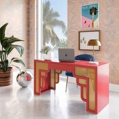 a laptop computer sitting on top of a red desk in front of a large window