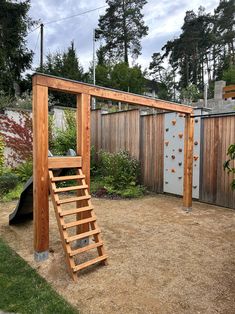 a wooden climbing wall in a backyard with steps leading up to the top and bottom