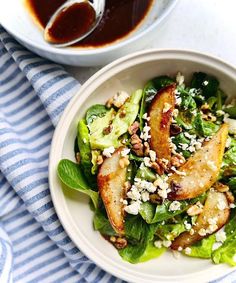 a white bowl filled with salad next to a blue and white striped napkin on top of a table