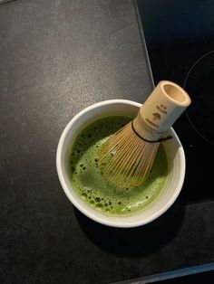 a whisk in a white bowl on top of a black counter next to an oven