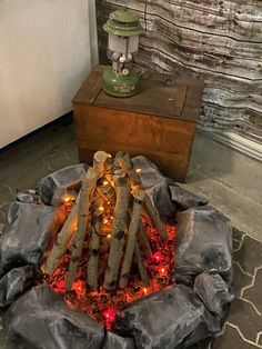 a fire pit made out of logs and rocks with lights around it on the floor