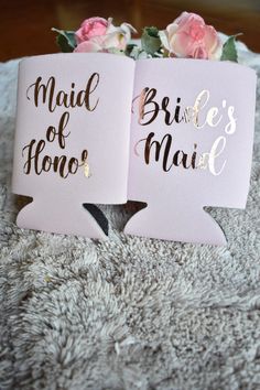 two pink and gold bride's maid signs sitting on top of a white blanket