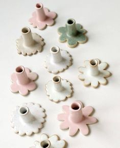 small ceramic flower vases in various colors and sizes on a white surface with one being used as a candle holder