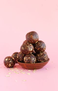 a wooden bowl filled with chocolate covered donuts on top of a pink tablecloth