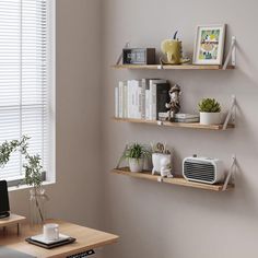 a desk with a computer, laptop and other items on it in front of a window