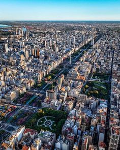 an aerial view of a large city with lots of tall buildings and green trees in the foreground