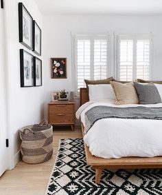 a bed sitting in a bedroom next to a window with shutters on both sides