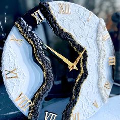 a black and white clock with gold roman numerals