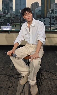 a young man sitting on top of a wooden floor next to a cityscape