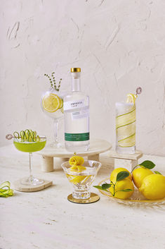 a table topped with lemons and glasses filled with alcohol next to eachother