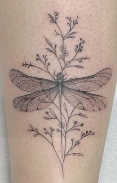 a black and white photo of a dragonfly on the thigh with flowers in it