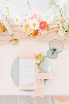 the table is set with pink and yellow flowers on it, along with an empty menu