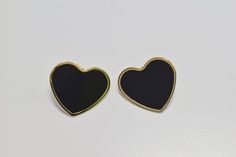 two black heart shaped earrings sitting on top of a white table