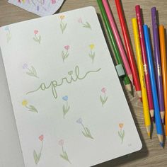 an open notebook with the word april written on it next to colored pencils and markers