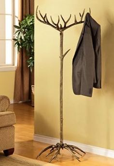 a coat rack with a jacket hanging on it next to a chair in a living room