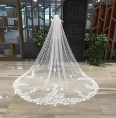 a white wedding veil with flowers on the bottom is hanging in front of a doorway