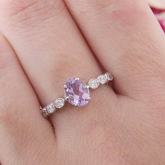 a woman's hand holding a ring with an amethorate and diamond band