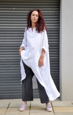 a woman standing in front of a garage door wearing a white shirt and black pants