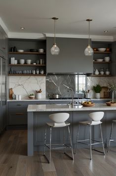 a kitchen with gray cabinets and white stools in front of an island countertop