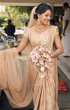 a woman in a beige sari holding a bouquet