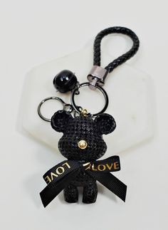 a key chain with a black teddy bear on it's side and an embellishment that says, not love