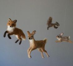 several stuffed animals hanging from strings in the shape of deer and squirrels, all on white background