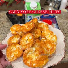 a person holding a plate full of cheese puffs on a counter top next to a carton of milk