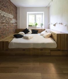 a bed that is in the middle of a room with wooden floors and brick walls