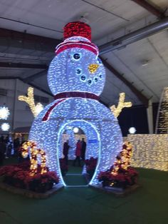 a snowman made out of christmas lights in the middle of a building with people standing around it