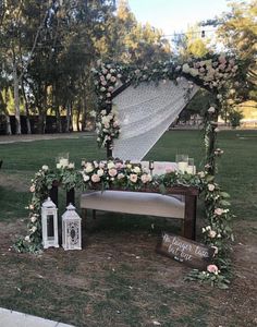 an outdoor ceremony setup with flowers and candles on the ground next to a wooden bench