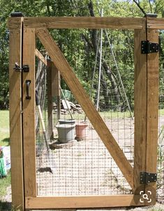 a wooden gate with metal latches on the sides and an animal enclosure behind it