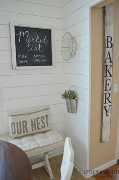 a white bench sitting in the corner of a room next to a chalkboard sign