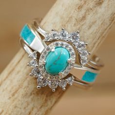 a turquoise stone surrounded by white diamonds sits on top of a piece of driftwood