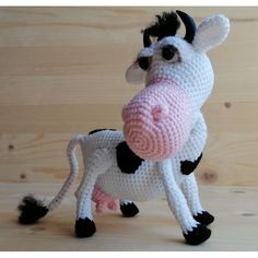 a crocheted cow is standing on a wooden surface