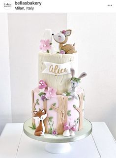 a three tiered cake decorated with pink and white fondant, woodland animals and trees